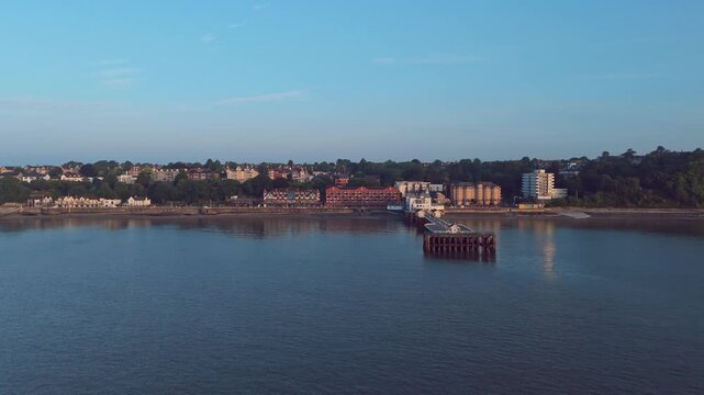 Aerial drone footage of Penarth seafront at sunrise overlooking the pier and residential areas. Tracking shot from right to left.