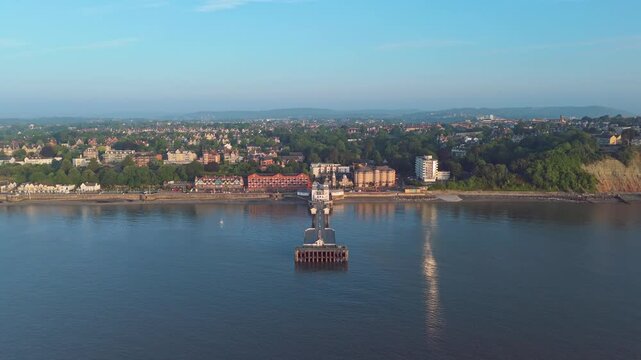 Aerial drone footage of Penarth seafront at sunrise overlooking the pier and residential areas. Ascending pull out shot.