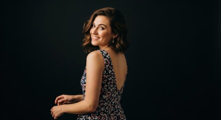 Smiling young caucasian female in floral dress against dark background