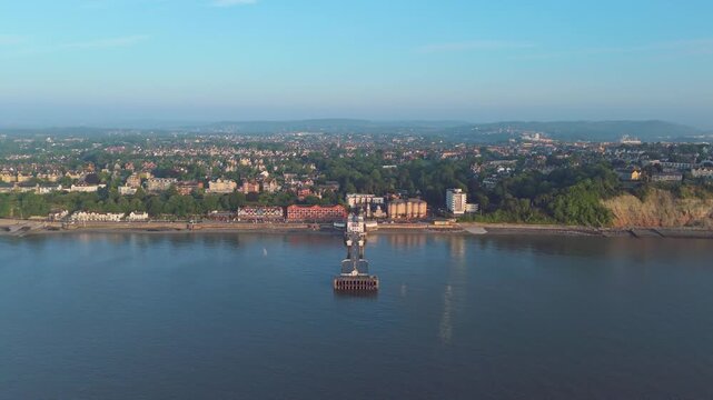 Aerial drone footage of Penarth seafront at sunrise overlooking the pier and residential areas. Descending push in shot.