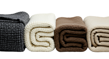 Four folded blankets in different textures and neutral colors displayed in a studio setting