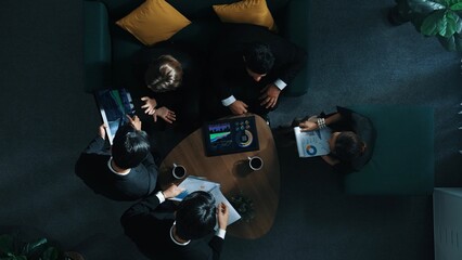 Top down aerial view of business people working together to plan marketing strategy while looking at financial graph from tablet. Group of skilled diverse people brainstorm creative idea. Directorate.