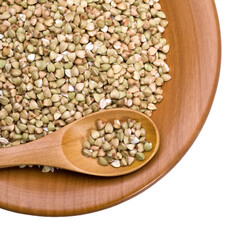Green buckwheat groats on wooden plate with spoon and transparent background
