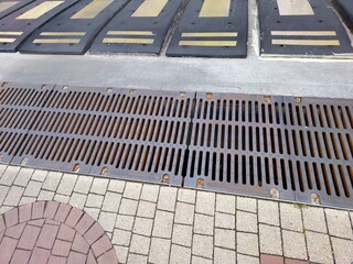 Fototapeta premium Sewer Grate Marking Entrance to Underground Parking Lot Surrounded by Patterned Pavement
