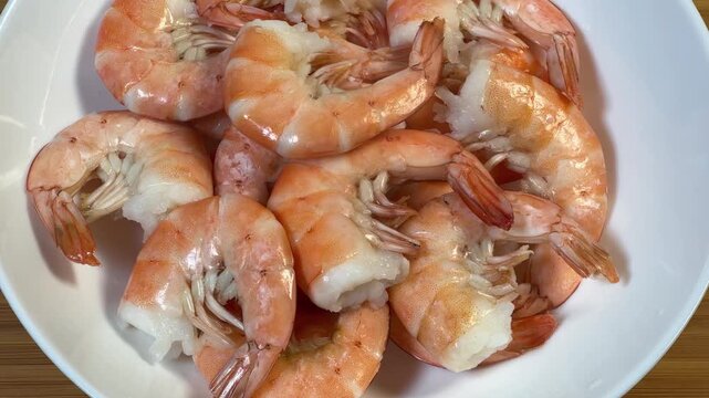 Boiled unshelled tails king prawns on white dish close-up
