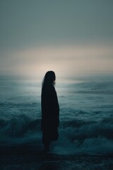 Silhouette of a person standing by the ocean during twilight