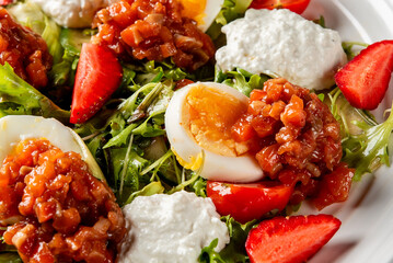 Fresh gourmet salad with strawberries, soft-boiled eggs, ricotta, tomato relish, and leafy greens....