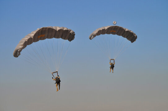 Two uniformed soldiers flying with parachutes