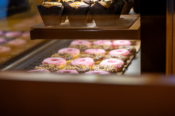 Pink Donuts, Muffins, and Other Sweets on Display in a Café Window
