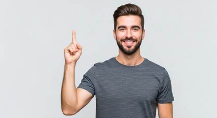 Fototapeta premium Young man with beard smiling and pointing finger up, isolated on white background