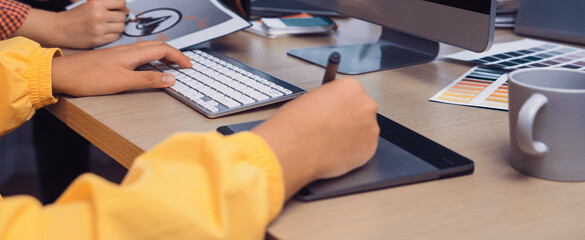 A vibrant creative workspace featuring a person using a digital drawing tablet next to a computer monitor, surrounded by color swatches and office supplies for inspiration. SACTR