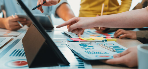 A dynamic scene of a collaborative meeting showcasing diverse hands engaged in discussion over data charts and digital devices in a modern office setting. SACTR