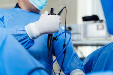 Doctor doing endoscopy in sterile setting. A medical expert in blue scrubs performs an endoscopy in...