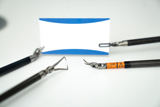 Dental instruments are arranged around a blank name card. Three dental tools are positioned near a blank name card on a clean surface, ready for use in a dental procedure.