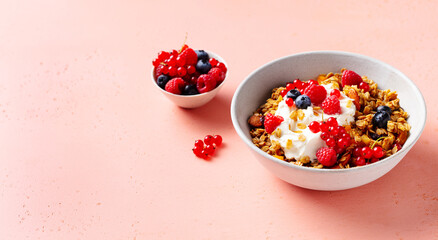 Healthy breakfast. Granola, muesli with yogurt and fresh berries. Pink background. Close up. Copy space.