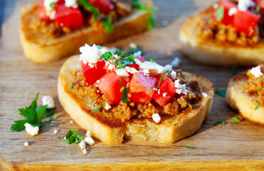 Bruschetta with olive tapenade and fresh tomatoes on cutting board. Wooden background. Close up.