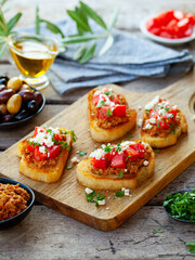 Bruschetta with olive tapenade and fresh tomatoes on cutting board. Wooden background. Close up.