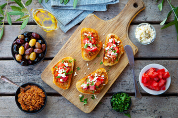 Bruschetta with olive tapenade and fresh tomatoes on cutting board. Wooden background. Top view.