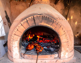Traditional brick oven with roasting artichokes and burning embers