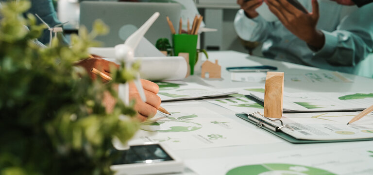 Engaging teamwork in a modern workspace focused on sustainability and innovative design solutions. Professionals discuss eco-friendly strategies amidst creative materials. SACTR