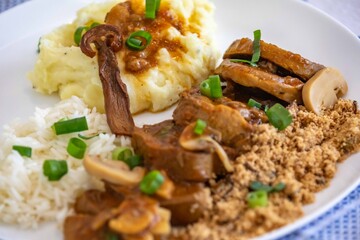 Traditional rustic Brazilian dish, beef tongue in Madeira sauce, mushrooms, rice, farofa and mashed potatoes