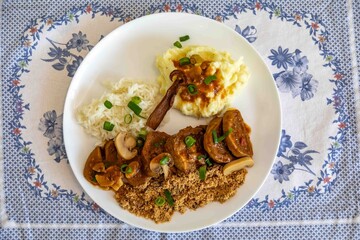 Traditional rustic Brazilian dish, beef tongue in Madeira sauce, mushrooms, rice, farofa and mashed potatoes