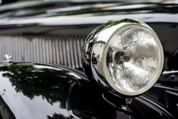 Fototapete Oldtimer Close-up of shiny headlight on a black vintage car   © Andrew