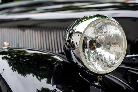 Fototapeta Close-up of shiny headlight on a black vintage car 