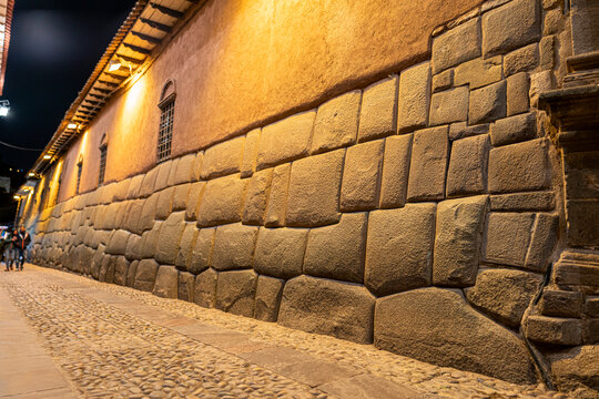 Hatun Rumiyoc street in Cusco, Peru, with the illuminated Inca stone wall at night, symbol of ancient Inca heritage and architectural mastery.