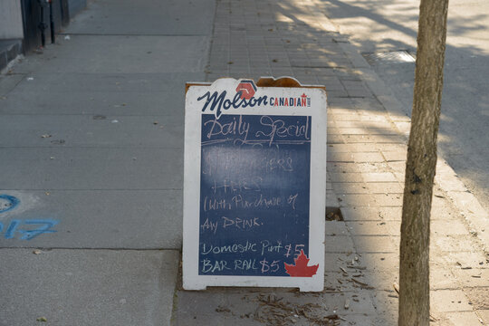 old sidewalk chalkboard with Molson Canadian branding outside a pub on Queen St E, Toronto