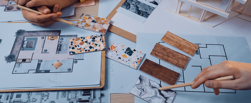 Hands examining color samples and floor plans, showcasing the collaborative and creative process of interior design and home renovation planning for artistic projects. SACTR