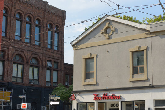 exterior building facade and sign of Tim Hortons, a coffee shop chain, located here at 800 Queen St E, Toronto (includes detail of historic building at 798 Queen E)