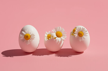 Photo of three white eggs and one egg with flowers inside on a pastel pink background,