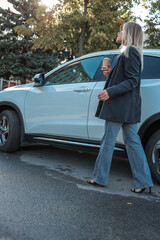 Woman with coffee exiting a white SUV on a sunny day