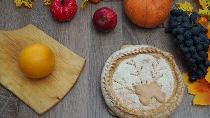 a woman is preparing a festive dinner at home. chicken with oranges. On the table there is pie and fruits, grapes, apples, pumpkin. Roasted Turkey. Thanksgiving table served . Christmas dinner
