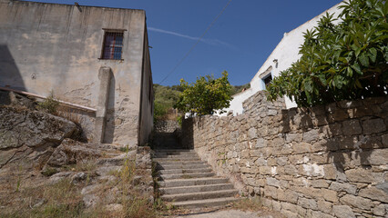 Narrow cobblestone street with rustic stone houses in traditional Sardinian village