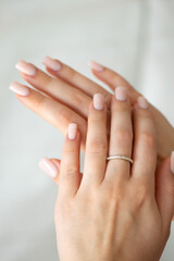 Naklejka premium Elegant female hands with nude manicure and silver ring