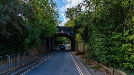 Car driving on a road passing under a low bridge in United Kingdom