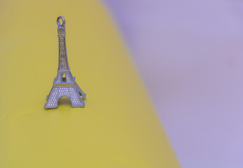 Miniature Eiffel Tower souvenir with word France on colorful yellow and purple background, travel concept for Paris tourism and culture