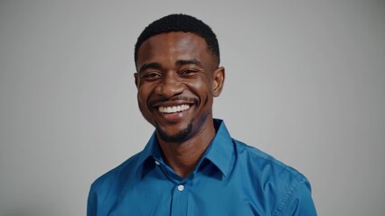 Fototapeta premium Smiling black man in a blue shirt. Portrait of a man in blue shirt. Professional standing in casual attire. A cheerful black man dressed in a blue shirt lifestyle.