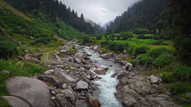Scenic mountain river flowing through a rocky valley with lush green hills, ideal for nature, travel, and landscape photography concepts.