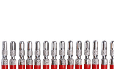 Close-up of many small, red-handled, metal-tipped screwdrivers, arranged in a horizontal row against a black background