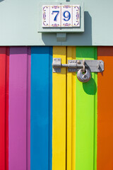 Brightly colored beach hut door in Brighton showcases vibrant stripes and a vintage lock, capturing a cheerful seaside atmosphere