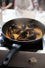 mejillones en una sartén cociéndose con caldo de marisco
