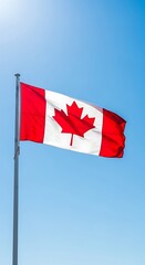 A vibrant Canadian flag billows proudly against a clear, bright blue sky.
