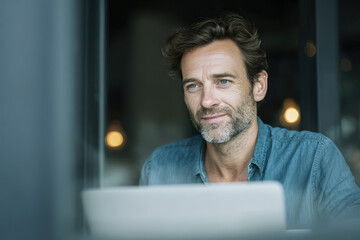 man with laptop is comfortably enjoying coffee in cozy corner of cafe surrounded by light gray background