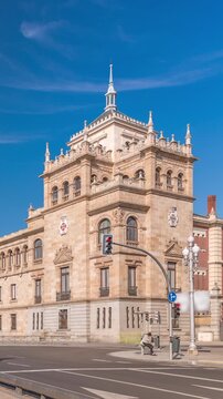 Timelapse of the Cavalry Academy in Plaza de Zorrilla, Valladolid, Spain. Historic military building with intricate architecture, surrounded by a busy urban scene under a blue sky with passing clouds.