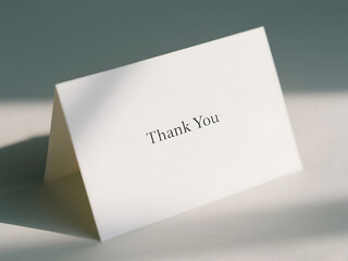Elegant thank you card with minimalistic typography standing on table in soft natural light