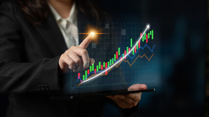 A business professional interacts with a digital tablet displaying vibrant financial graphs, symbolizing growth and strategic analysis in a corporate environment. Impute