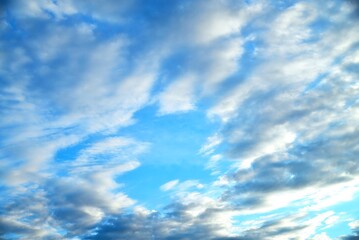 clouds of different shapes in the blue sky illuminated by the sun's rays